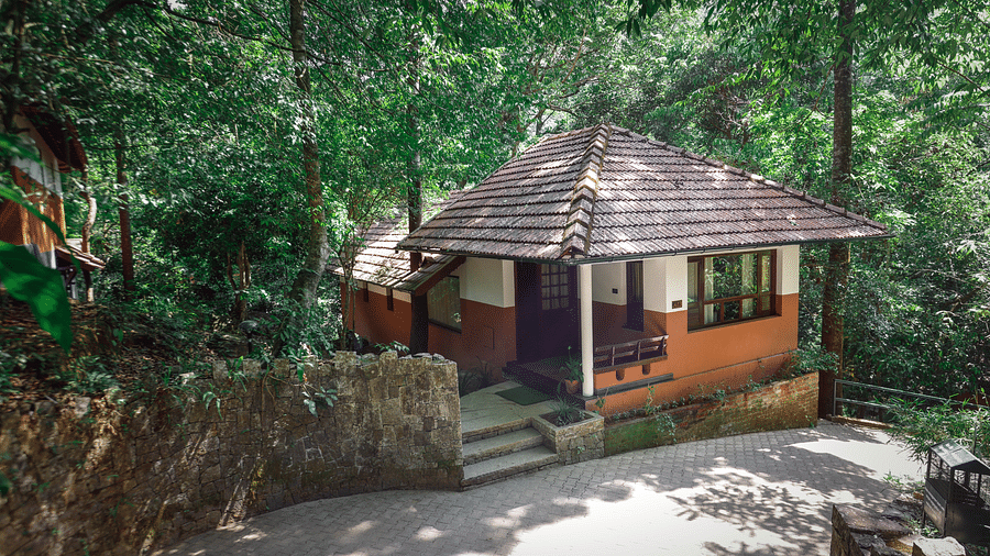 An exterior view of a steep-tiled villa nestled in greenery | Vythiri Resort. Wayanad
